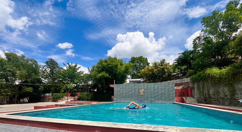 Guest swimming in the pool with the hills behind, at Ayu In The Hills